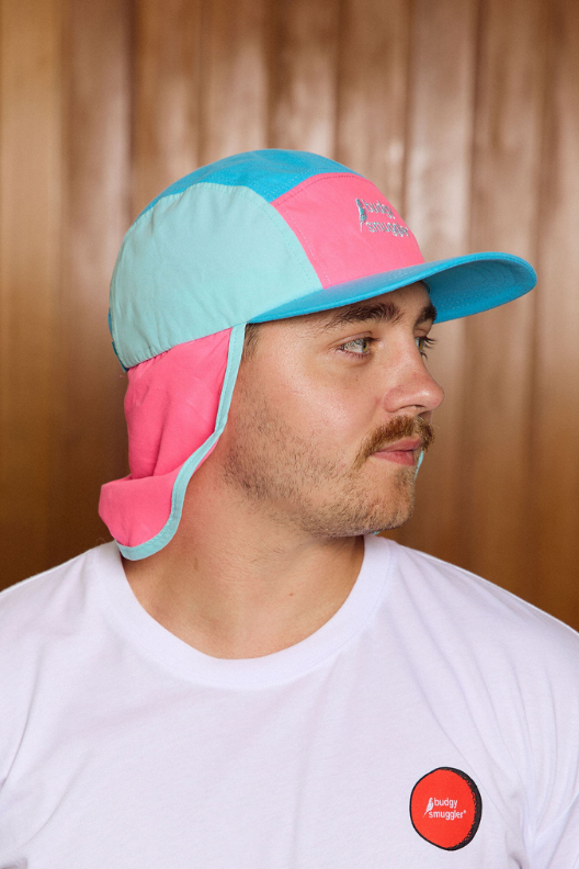 Man wearing a colorful hat and white t-shirt with a red logo indoors.